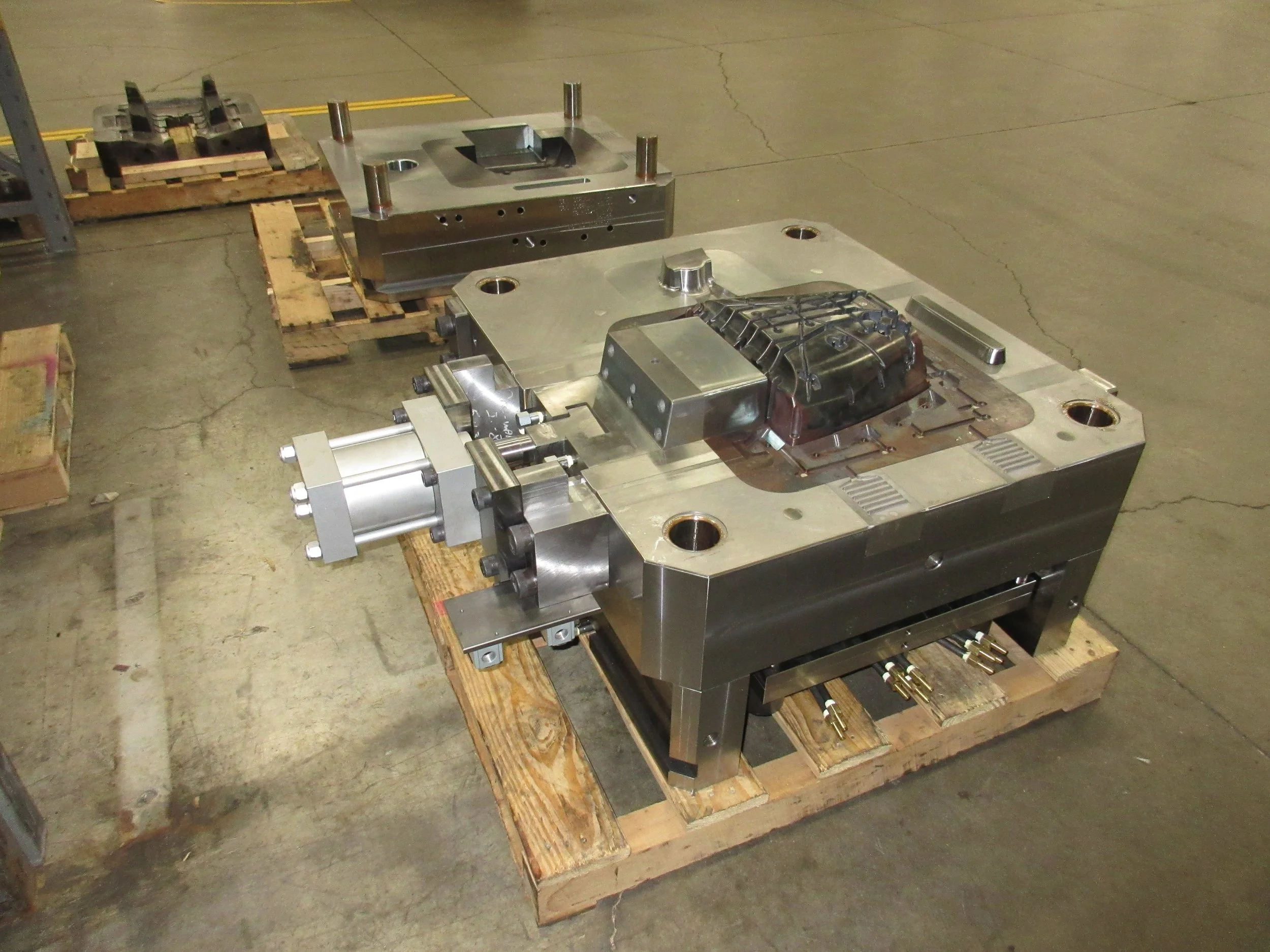 Large metal mold or industrial part resting on wooden pallets in a warehouse.