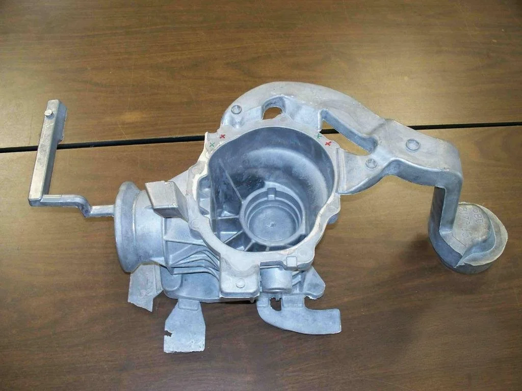 Metal automotive part on brown wooden surface.