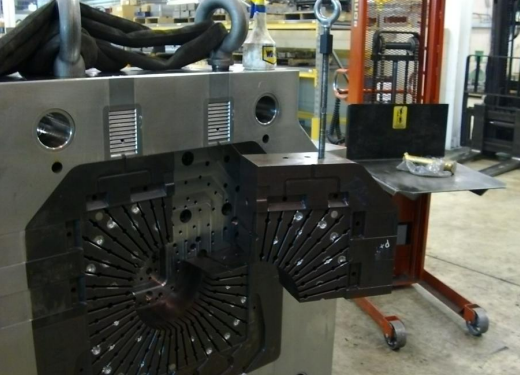 Close-up of industrial machinery with black segmented components and metallic elements in a manufacturing setting.