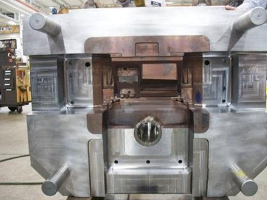 A large industrial metal mold or machine part in a workshop setting.