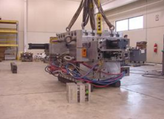 Heavy machinery in a warehouse with cables and equipment nearby.