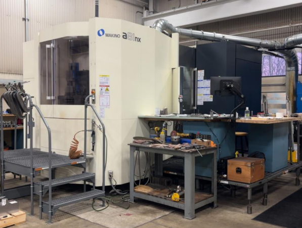 Industrial CNC machine in a workshop with workbenches and tools.