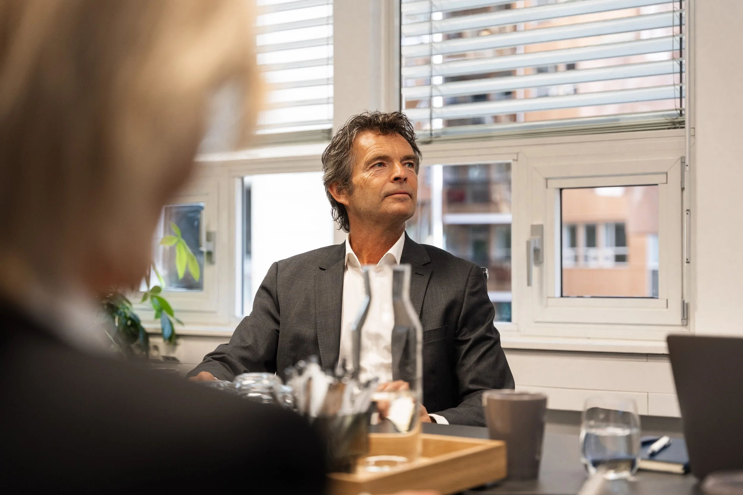Mann i dress sitter i et møte på et kontor.