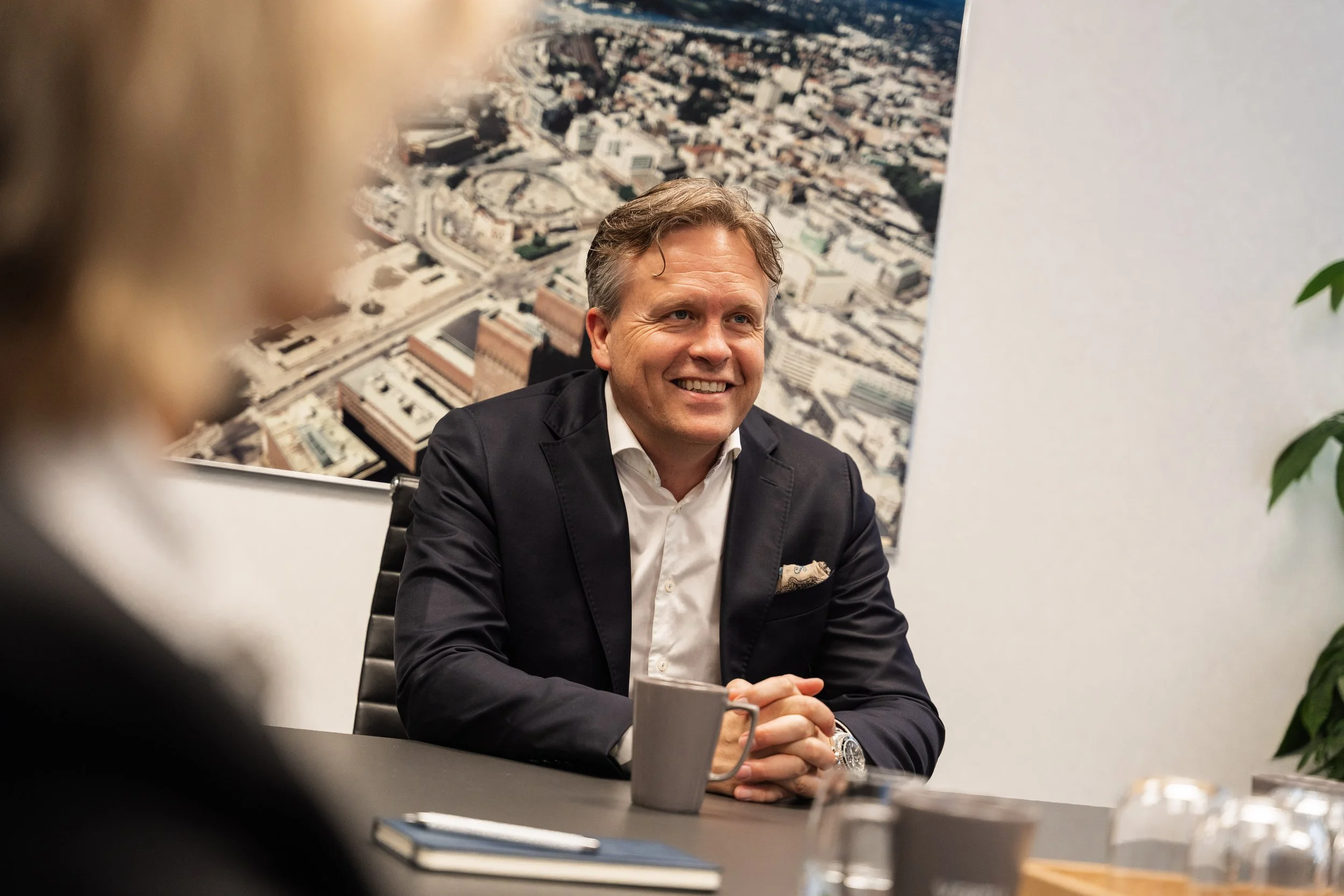 Mann i dress sitter i møte på et kontor.
