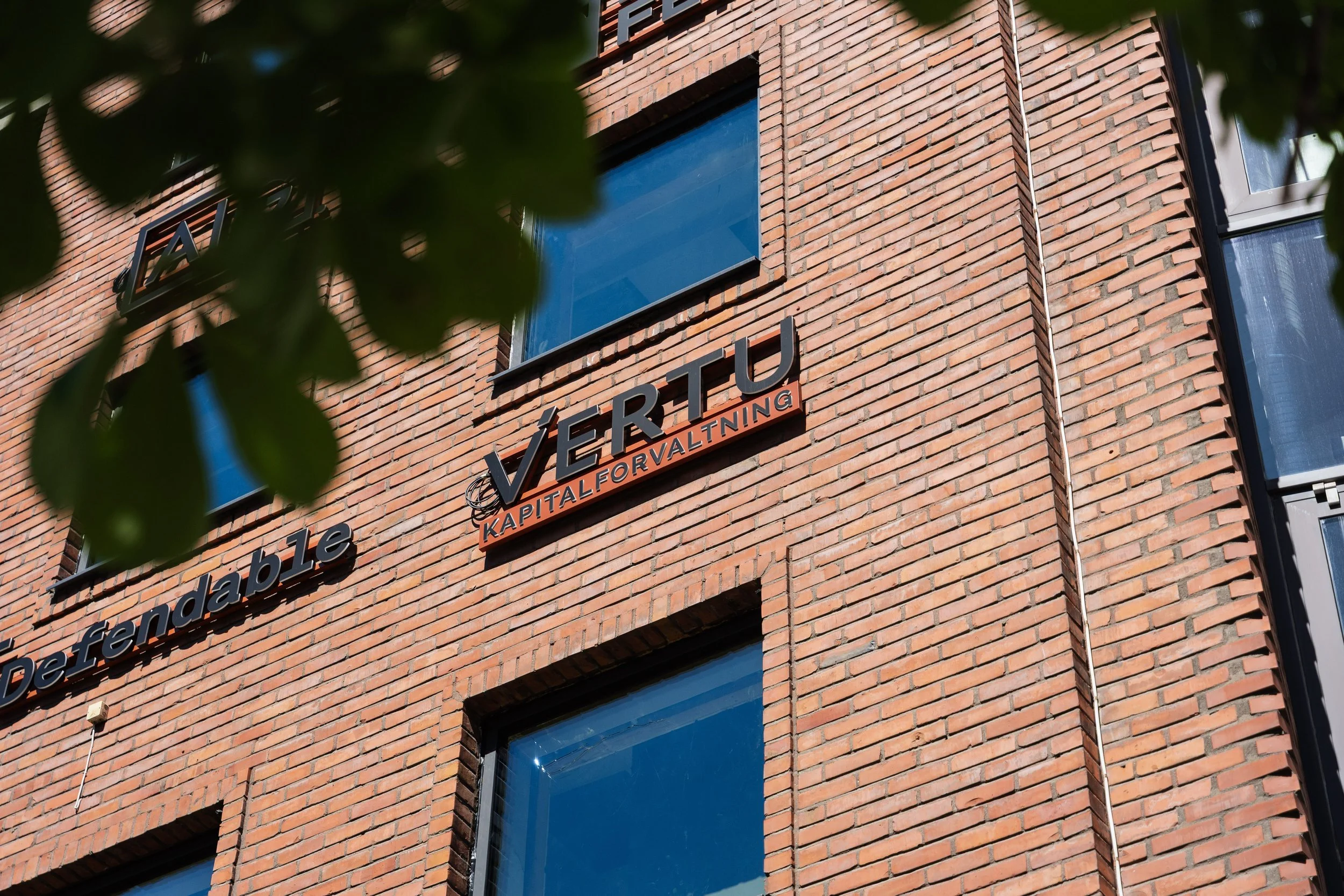 Utsiden av Vertu Kapitalforvaltnings kontorbygg med Vertu-logoen på fasaden.