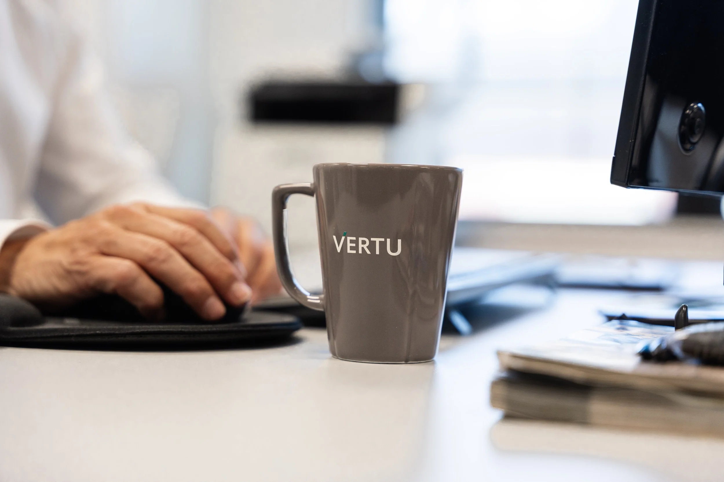 Kontorarbeid med VERTU-kaffekopp og datamaskin.