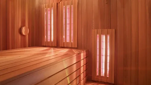 Interior of a wooden sauna with infrared lights on the walls and ceiling.