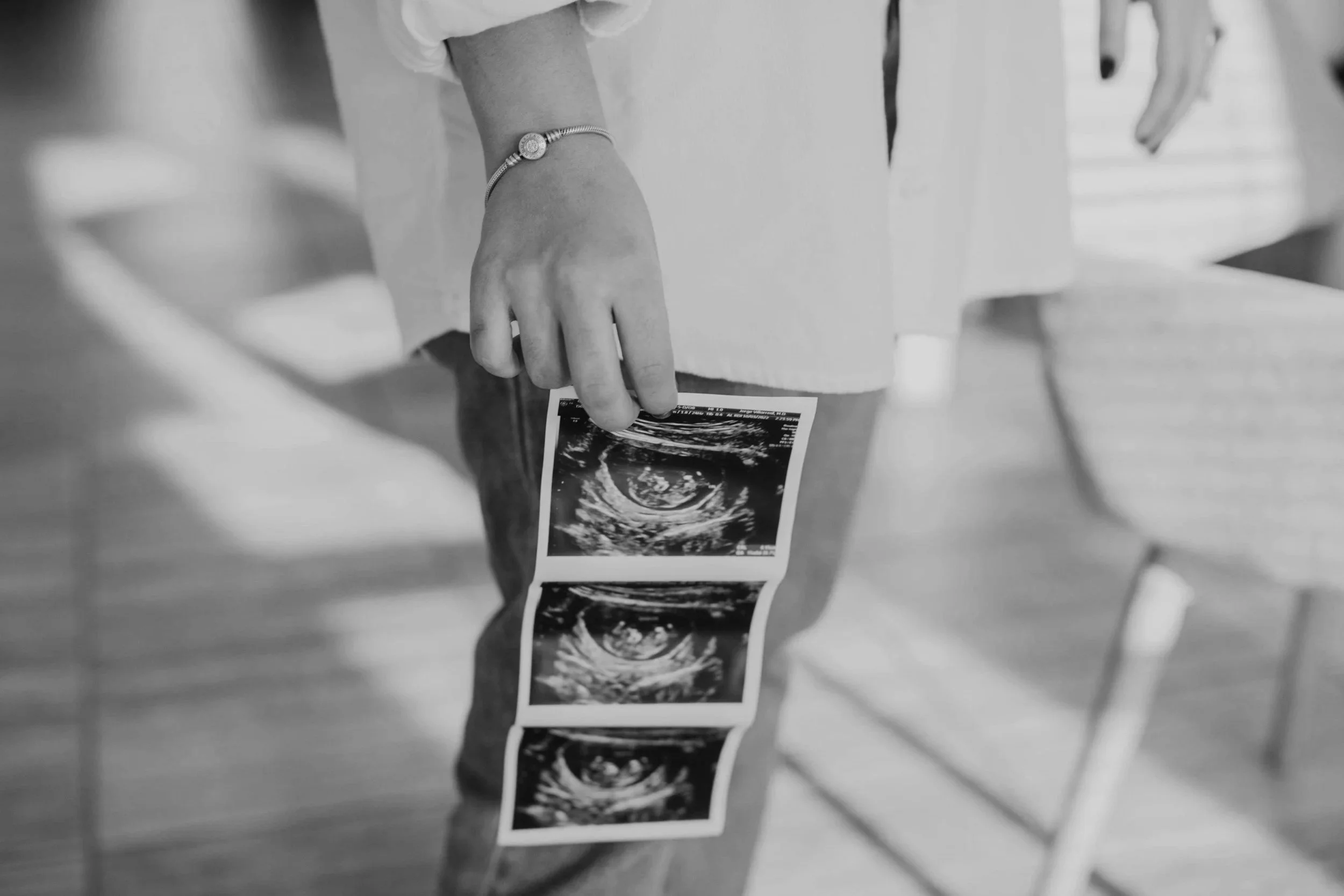 A woman holding ultrasound images in her hand in a black and white photo.