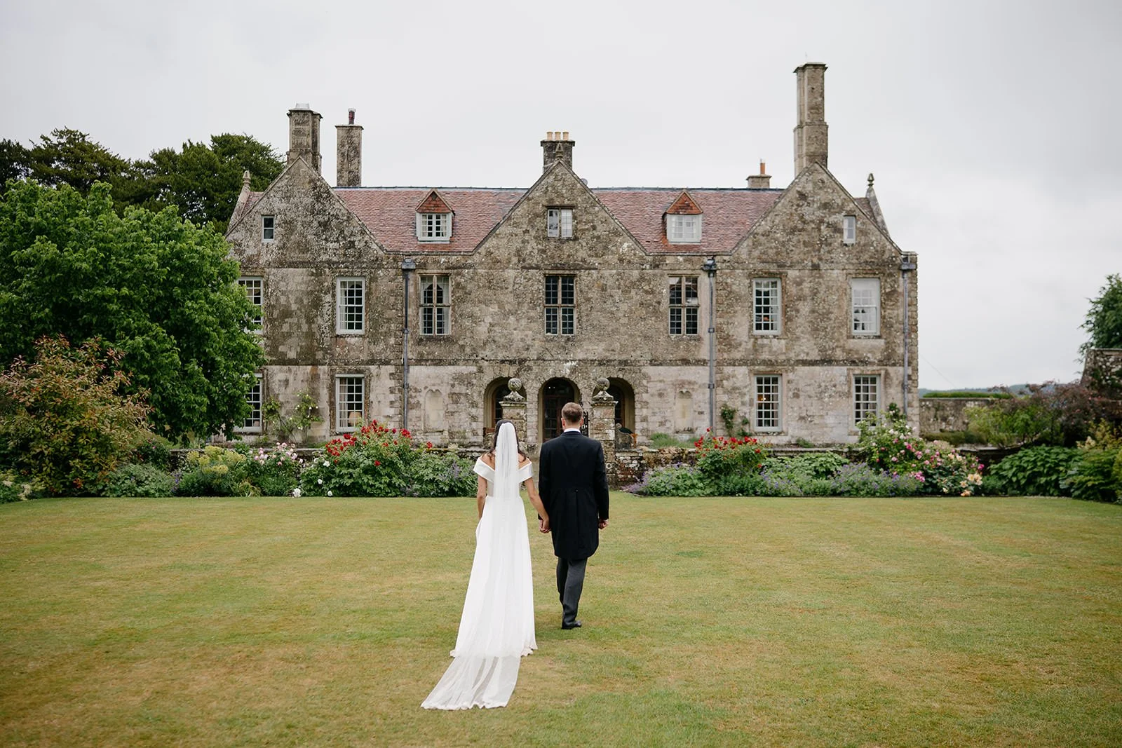 A bride and groom walking hand in hand towards wedding venue.
