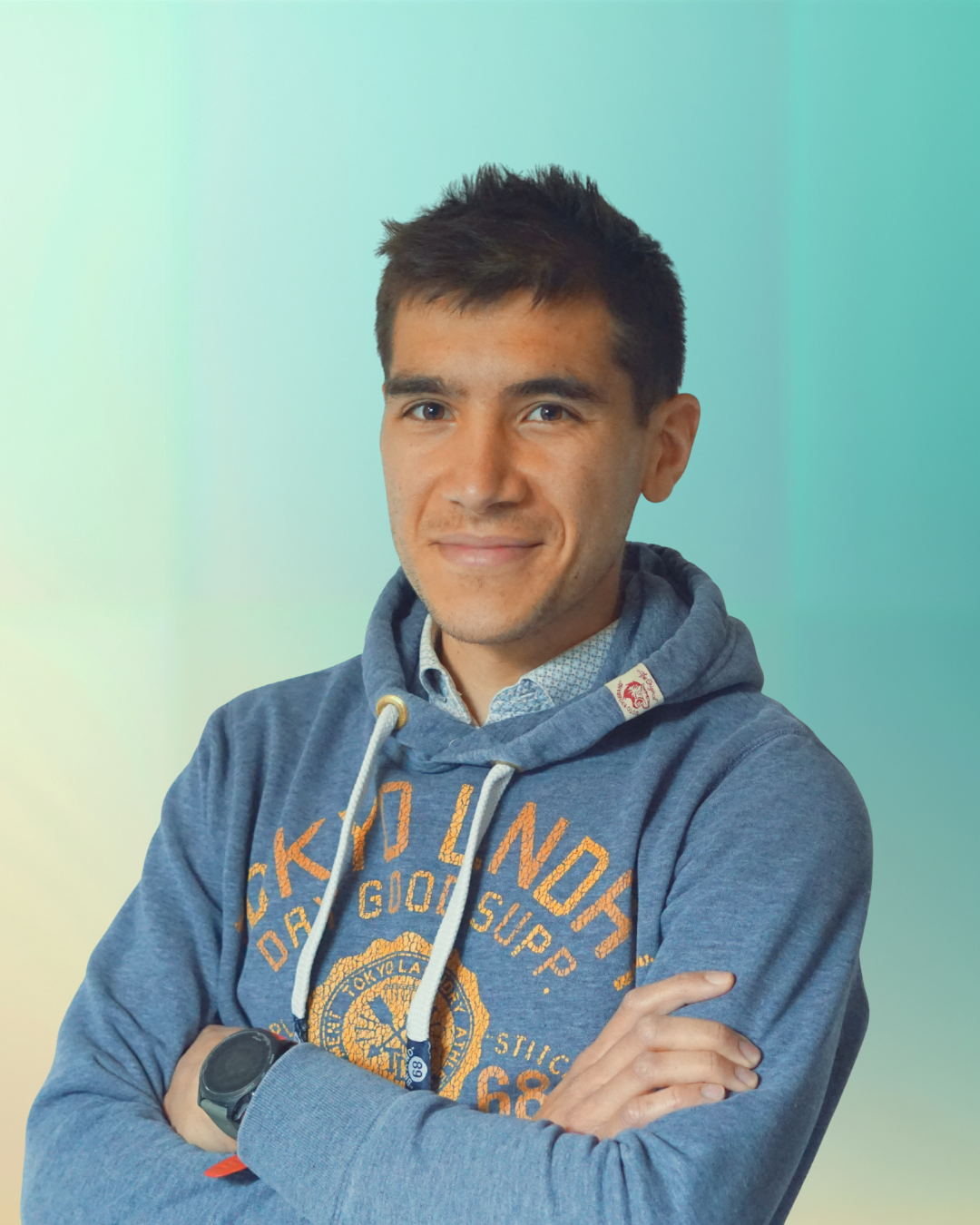 Un jeune homme souriant, portant un sweat à capuche bleu avec un design Orange et une montre, posé contre un fond dégradé vert et bleu.