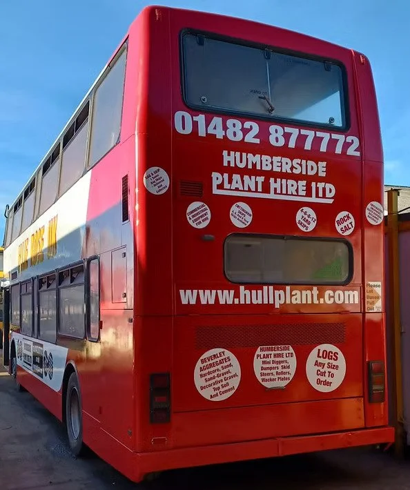 Red double-decker bus with advertisements for Humberside Plant Hire Ltd and website www.hullplant.com, parked outdoors under a blue sky.