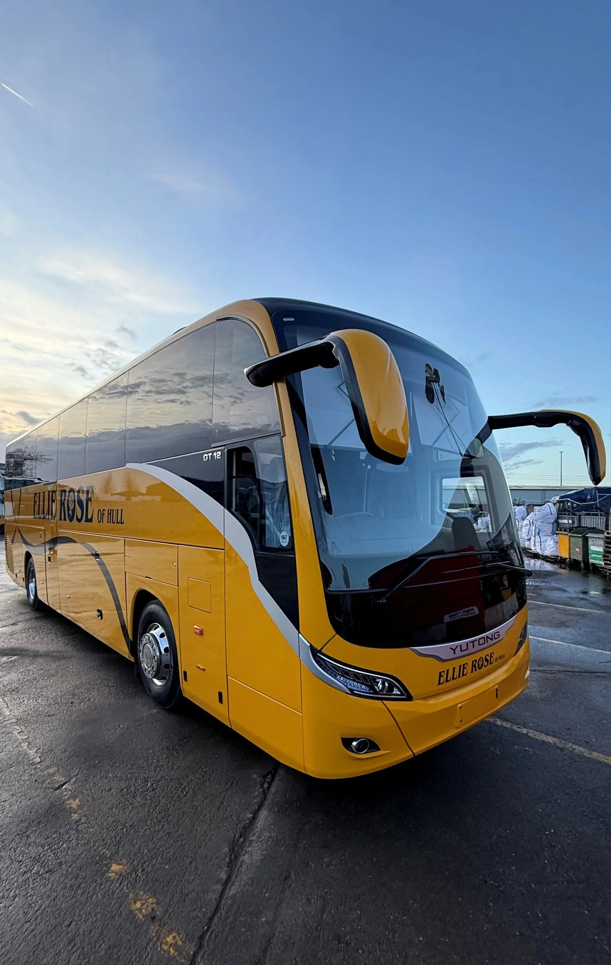 Yellow double-decker bus with the words 'Ellie Rose of Hull' parked on wet pavement under a partly cloudy sky.