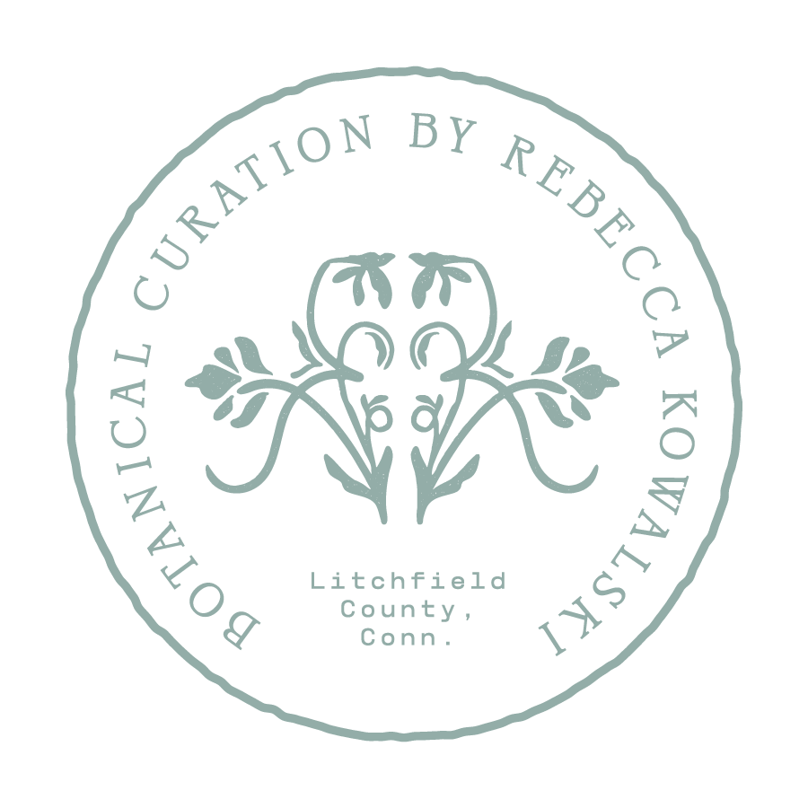 A circular badge with the text 'Botanical Cureation by Rebecca Kowalski' around the edge and 'Litchfield County, Conn.' in the center. The badge features a stylized floral design in the middle.