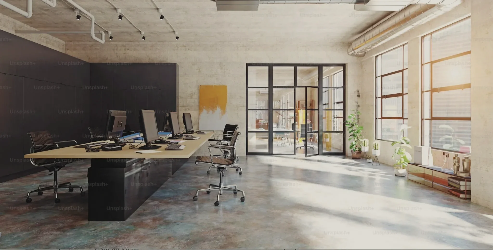 Top-down view of a minimalistic workspace with a closed silver laptop, white mouse, glass of beverage, pink notepad with gold pen, and various stationery items arranged on a white surface.