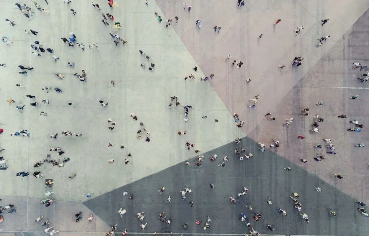 Aerial view of many people crossing a large paved city square