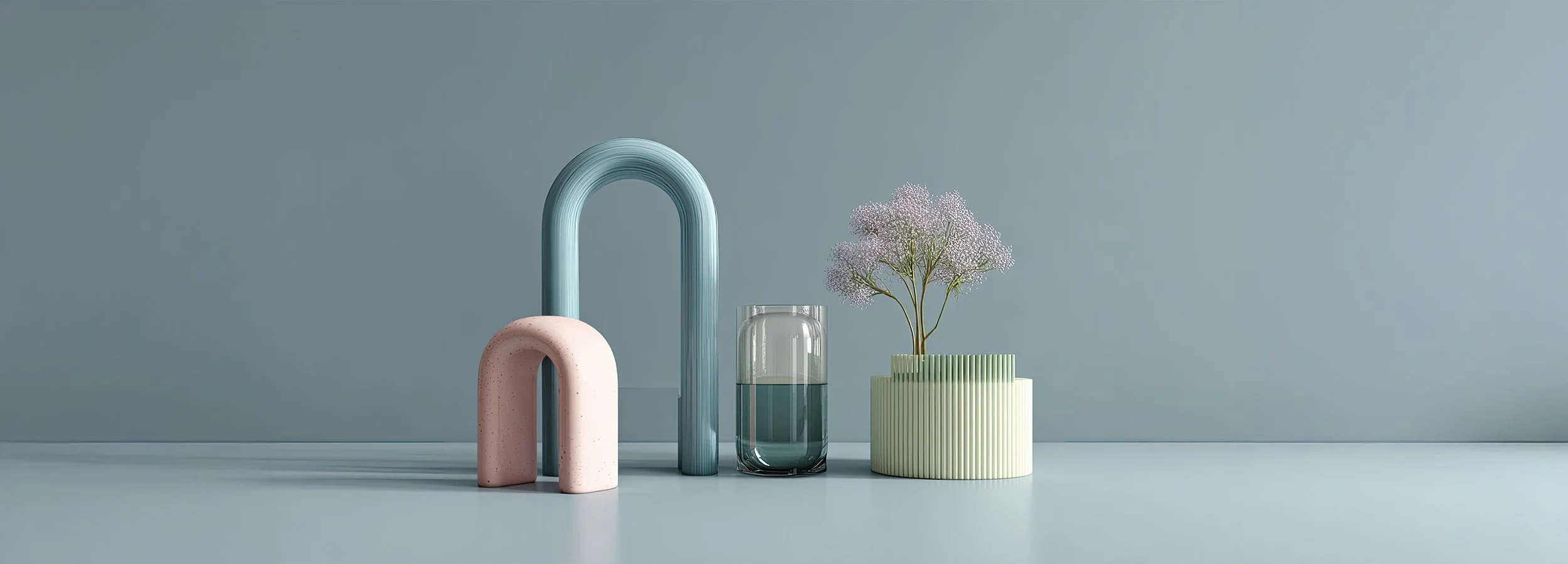 Minimalist decorative arrangement with pastel-colored art pieces, a glass of water, and a pink flower in a striped pot against a light blue background.