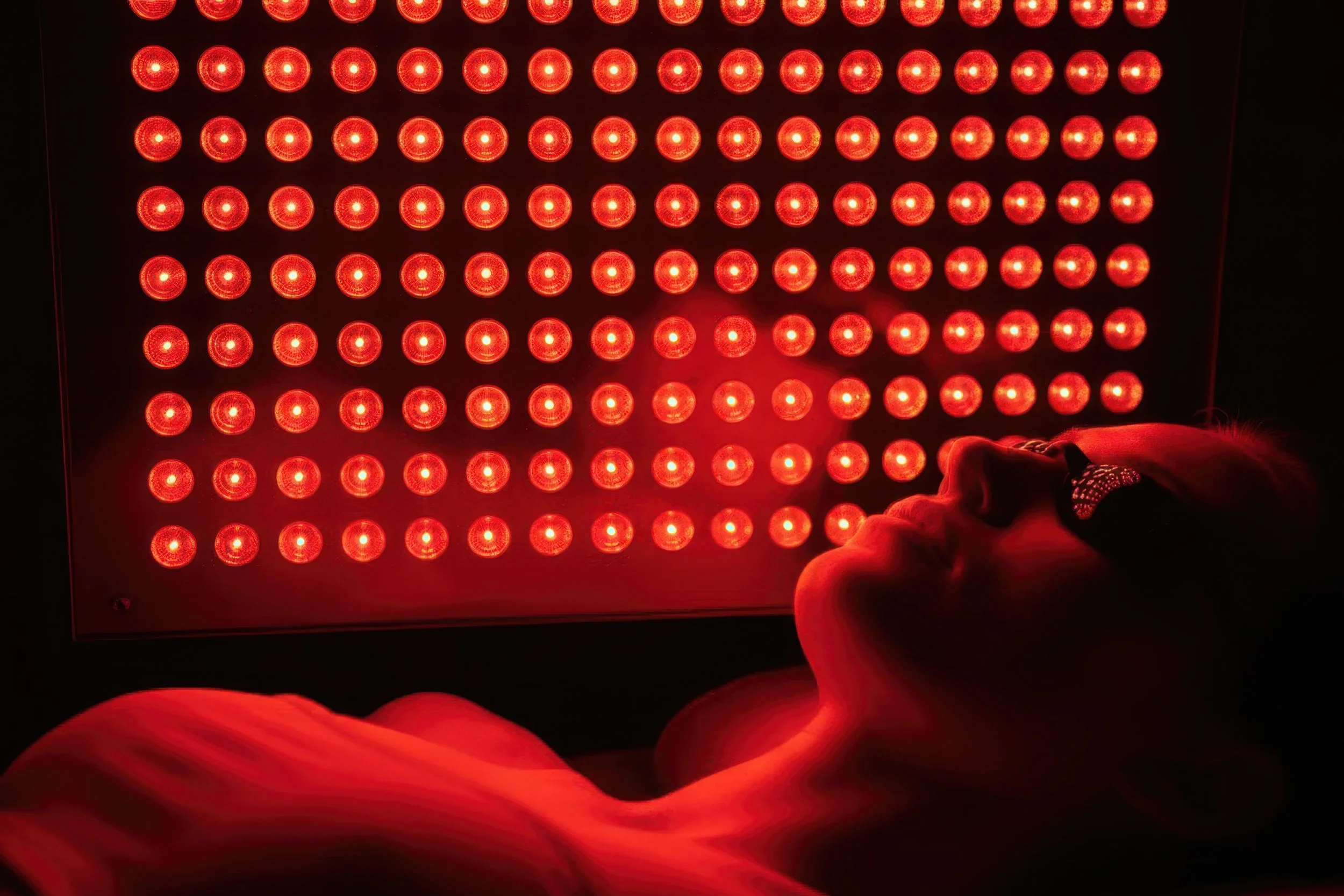 Une personne allongée et portant des lunettes à proximité d'un panneau de lumières rouges
