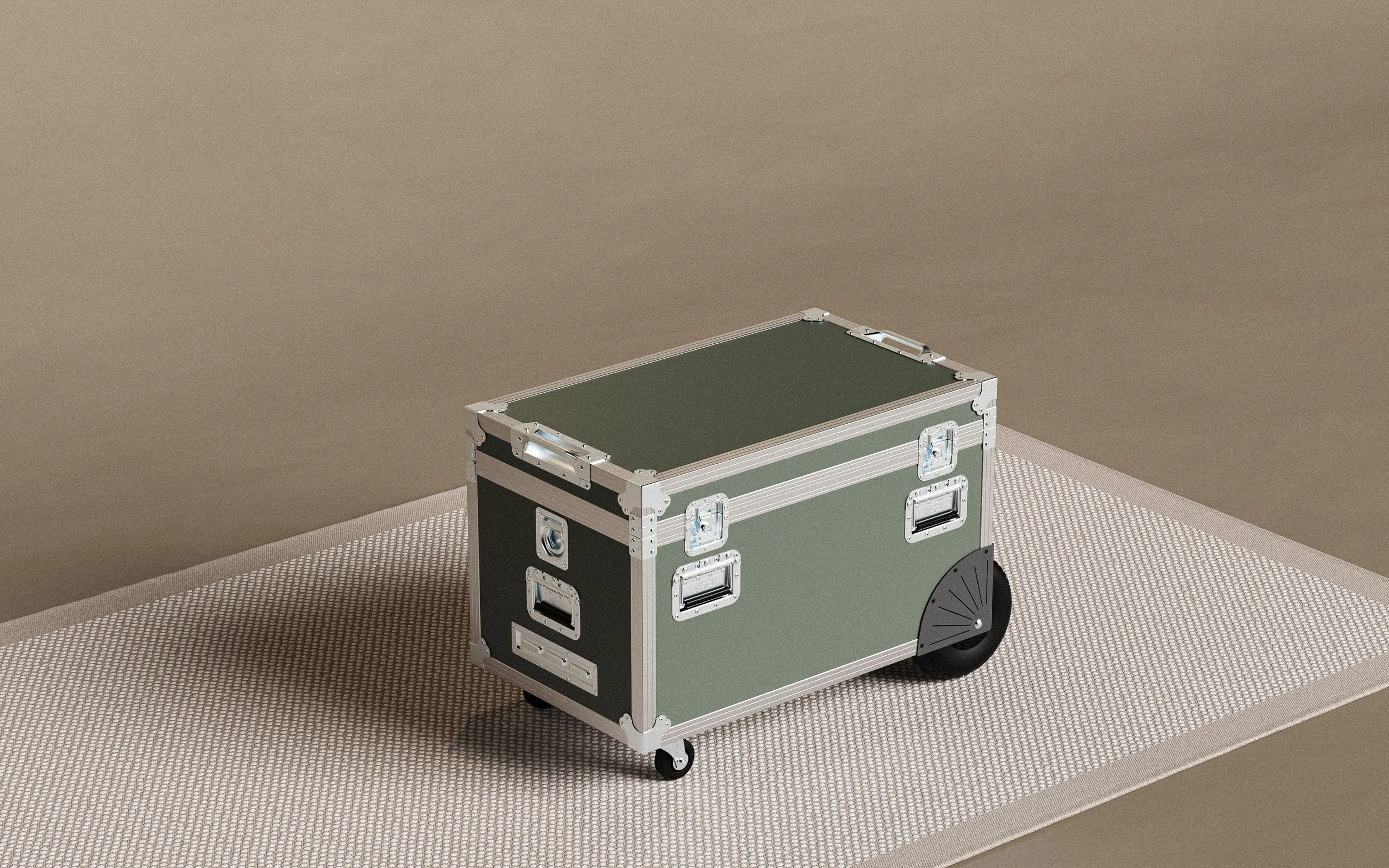 A green and black portable equipment case with metal reinforcements and wheels, placed on a beige textured mat on a brown floor.