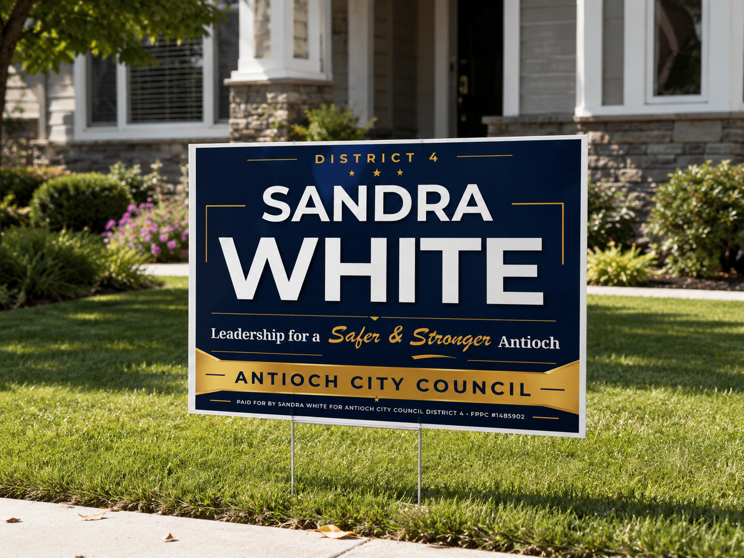 Campaign sign for Sandra White, running for Antioch City Council in District 4. The sign is placed on a lawn in front of a house, with flowers and bushes in the background.