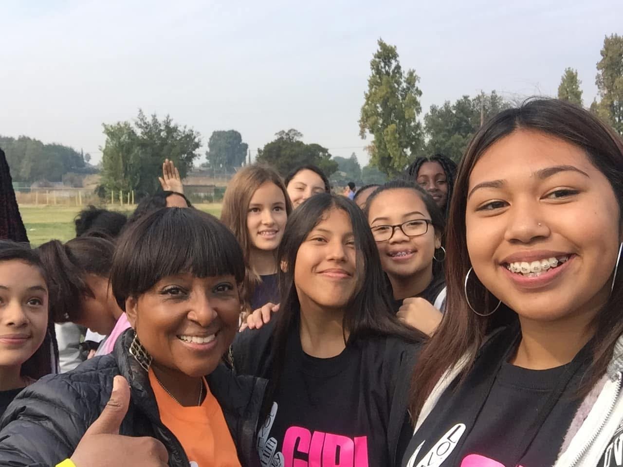 Sandra White with a group of smiling diverse young women from a girls empowerment event, a collaboration between Antioch Rotary Club and Antioch Unified School District.