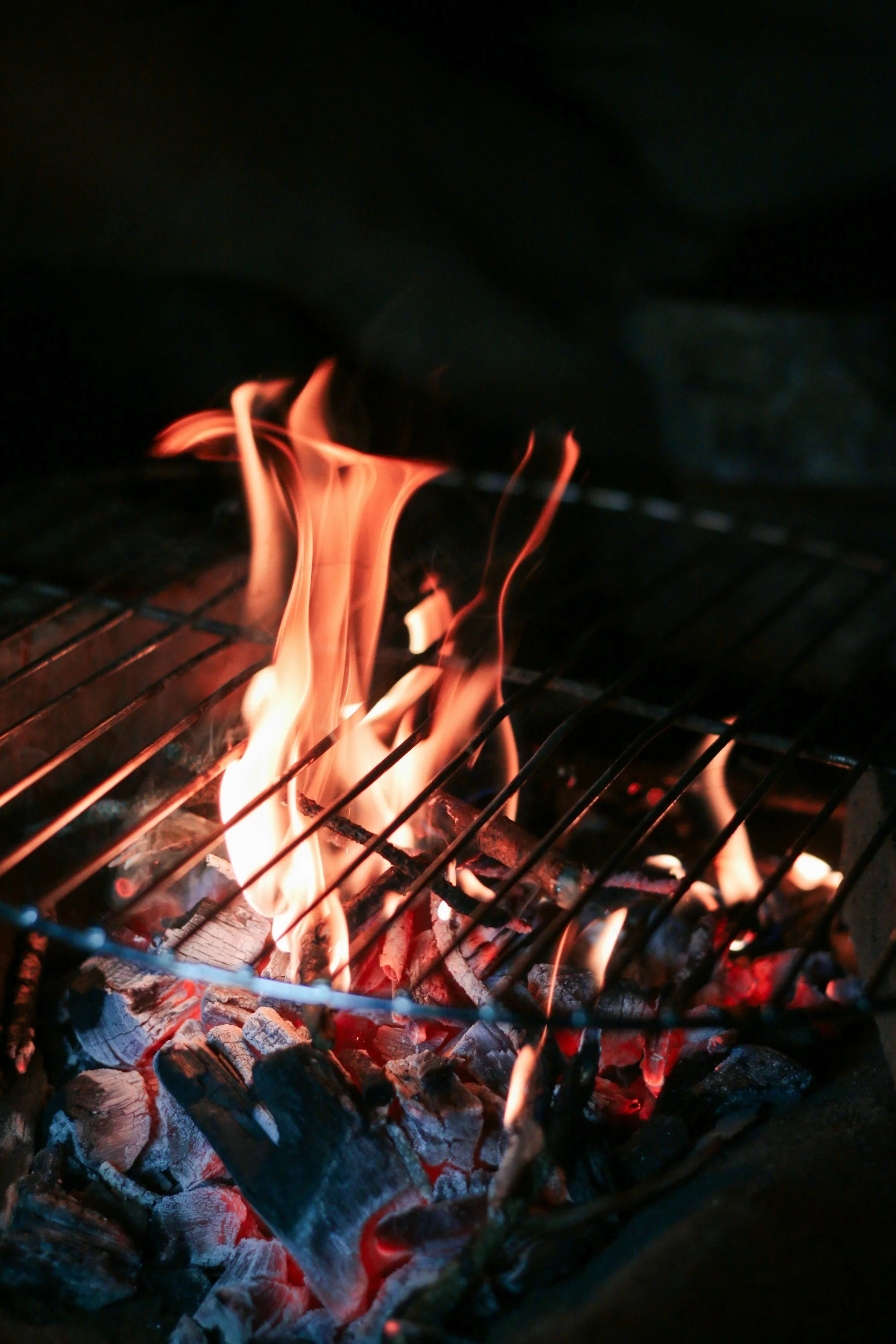 Close-up of a barbecue grill with burning charcoal and flames.