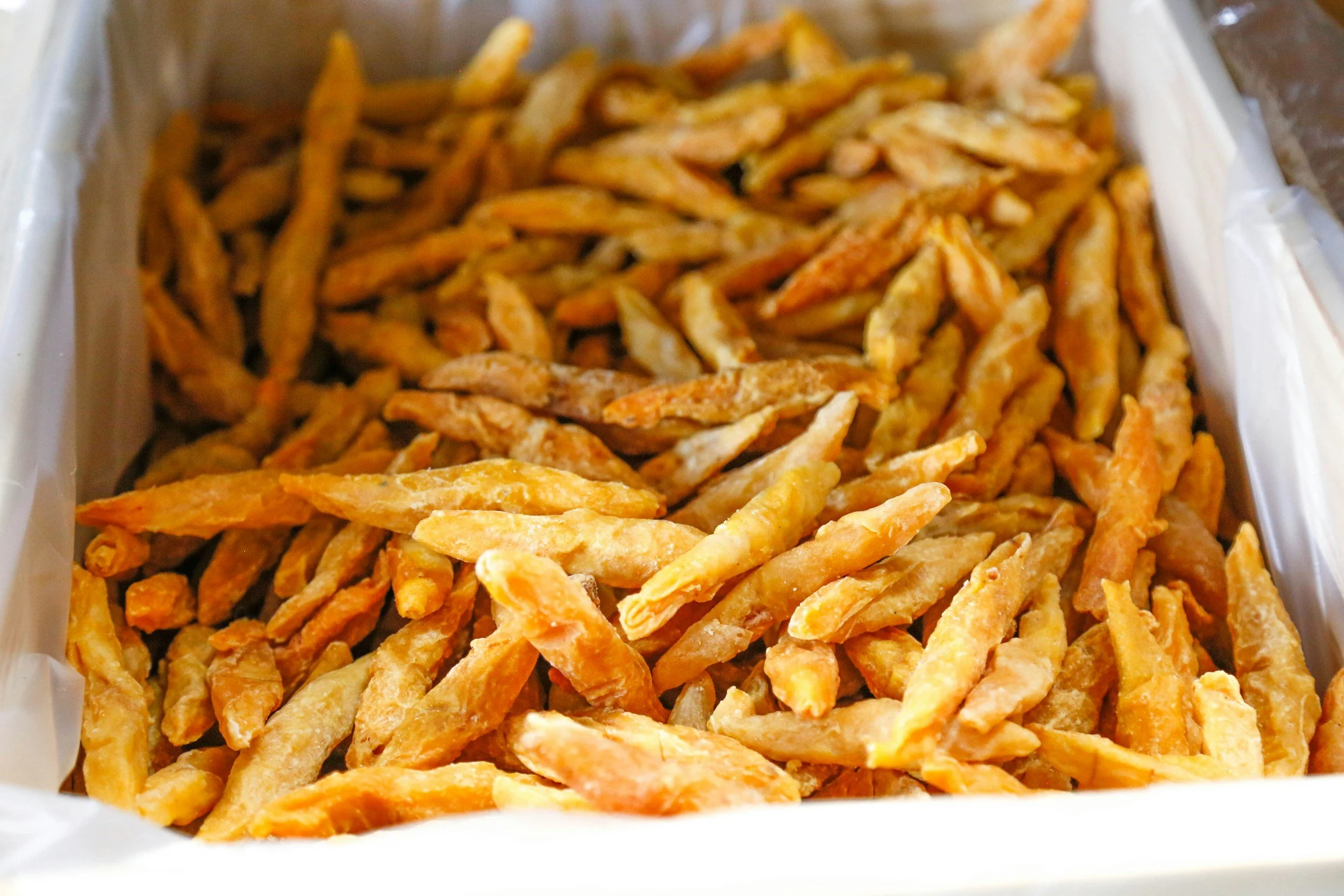 A tray of fried strips, possibly seasoned or coated, with a golden-brown appearance.