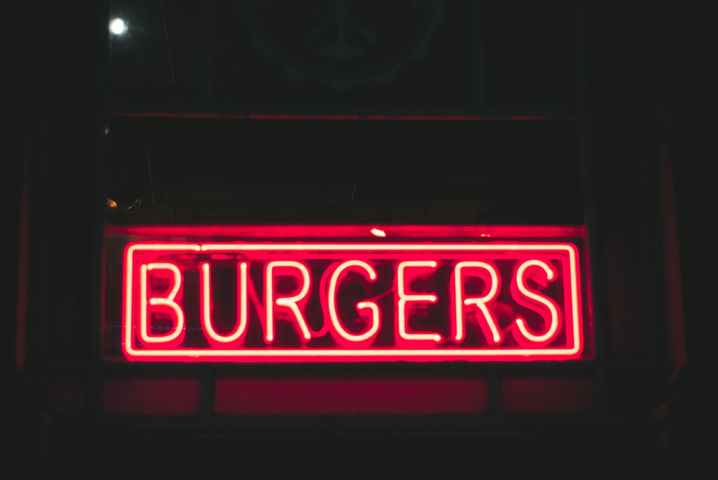Red neon sign with the word 'BURGERS' in capital letters.