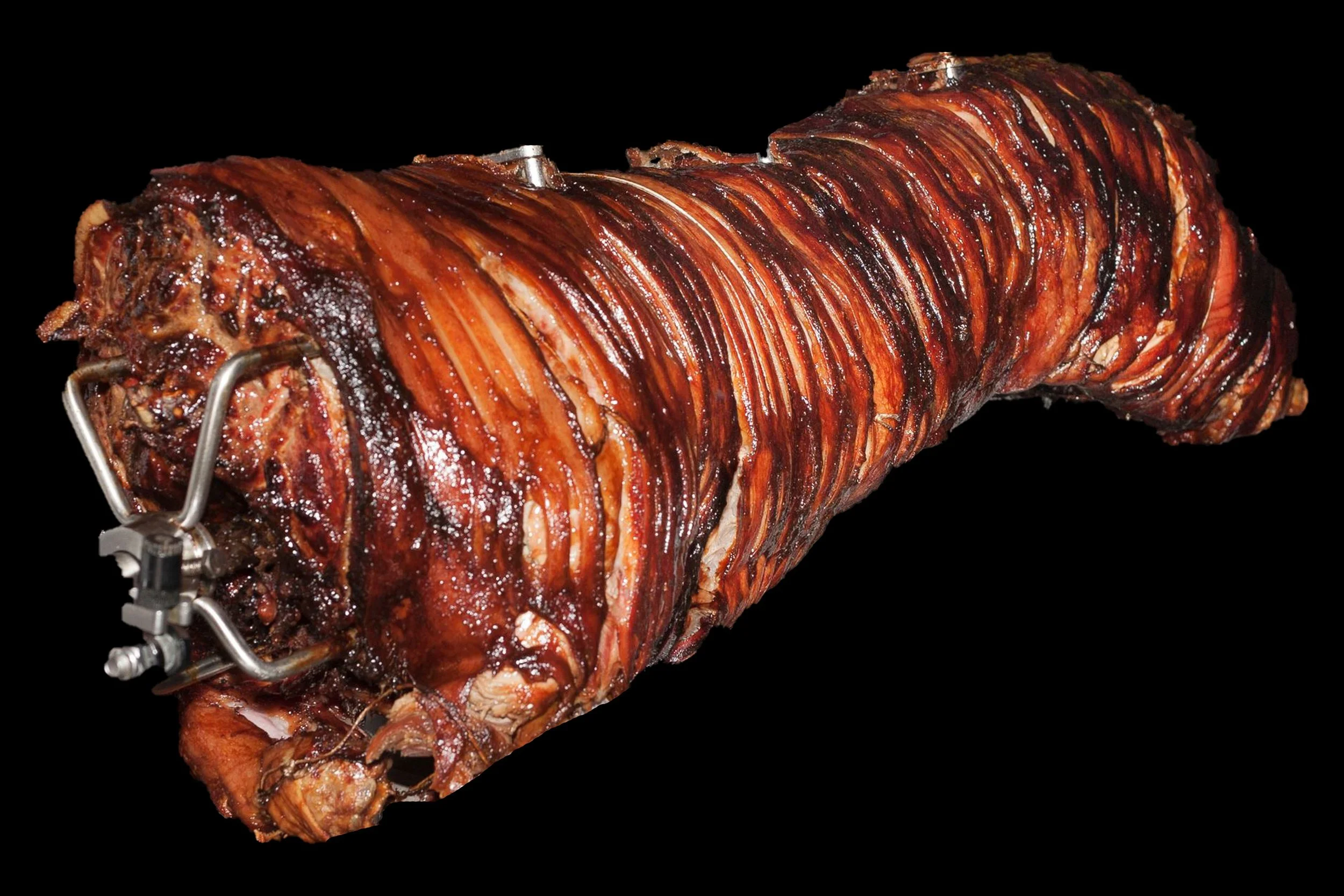 Smoked barbecue pig roast with crispy, glazed skin on a black background.