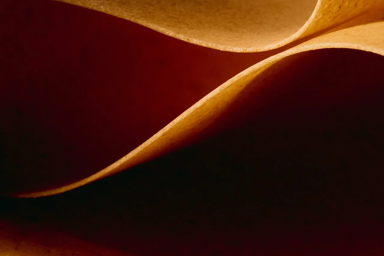 Close-up of curling, layered sheets of paper or material in shades of brown and beige.