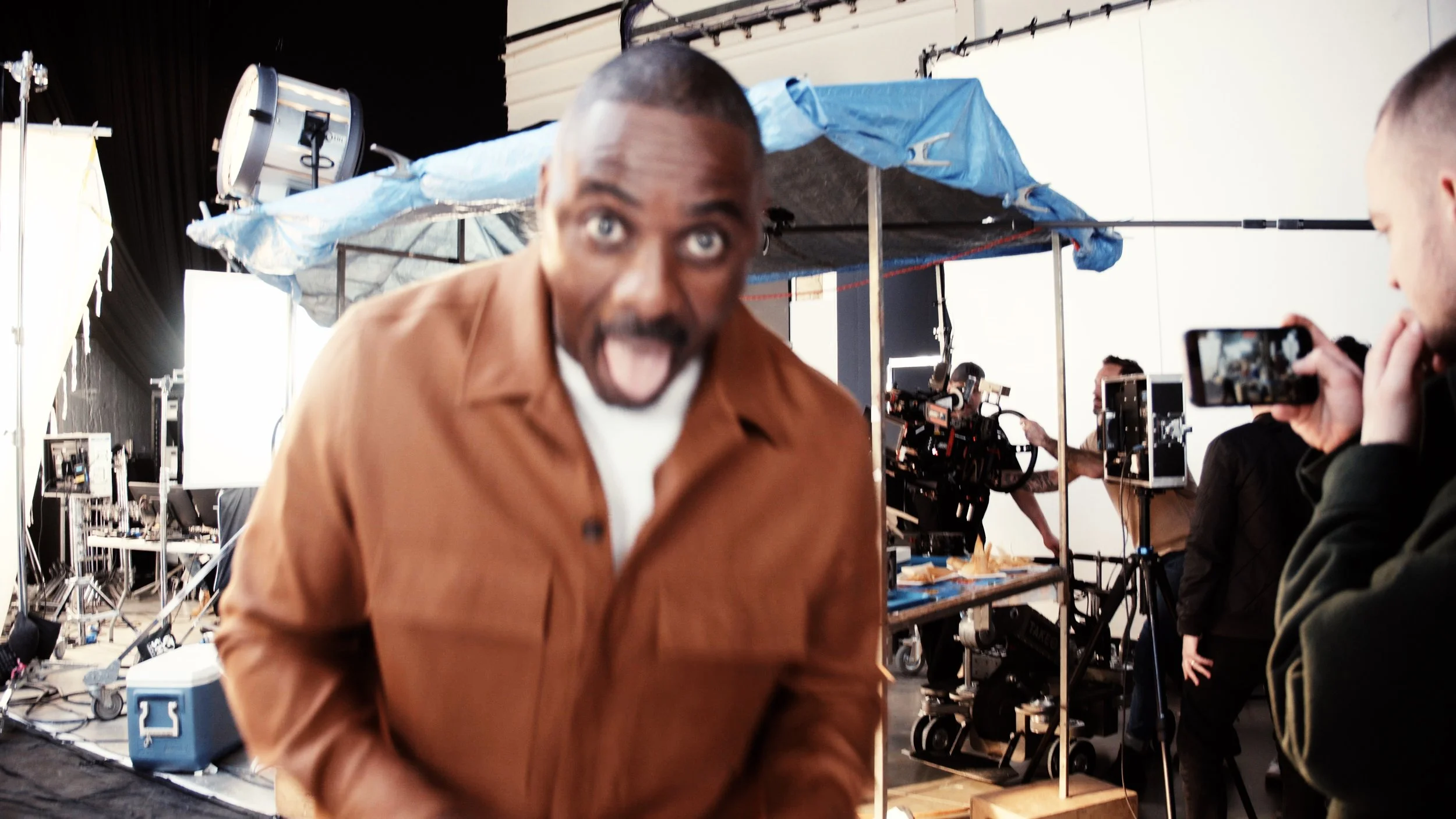 Idris Elba making a silly face at the camera behind the scenes