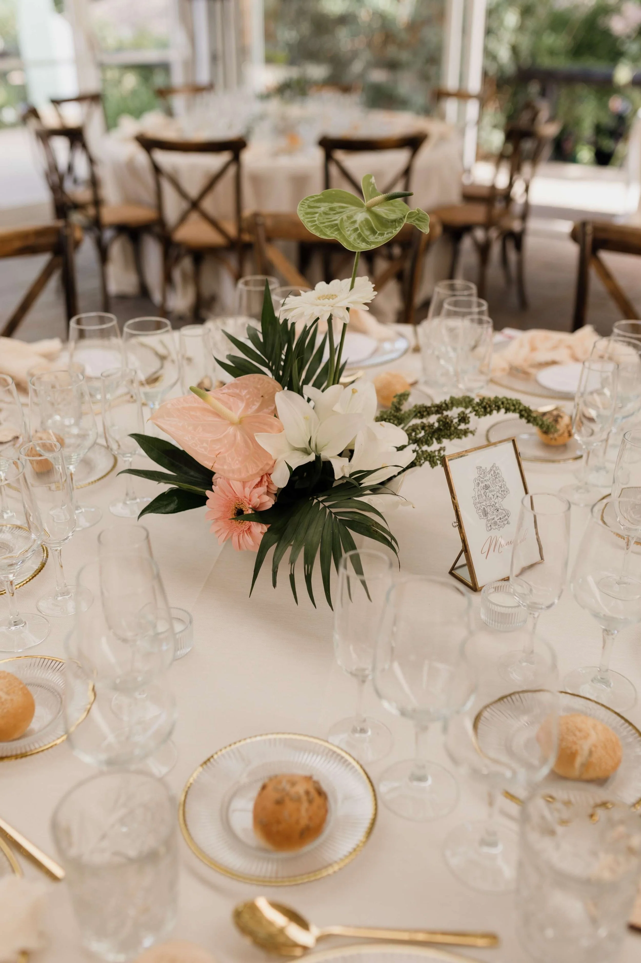 Elegant dining table set for a wedding or formal event with a floral centerpiece, champagne glasses, and gold-rimmed plates.