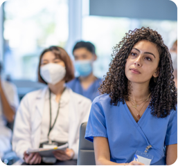 A group of healthcare professionals, including a woman in blue scrubs, standing in a medical setting.