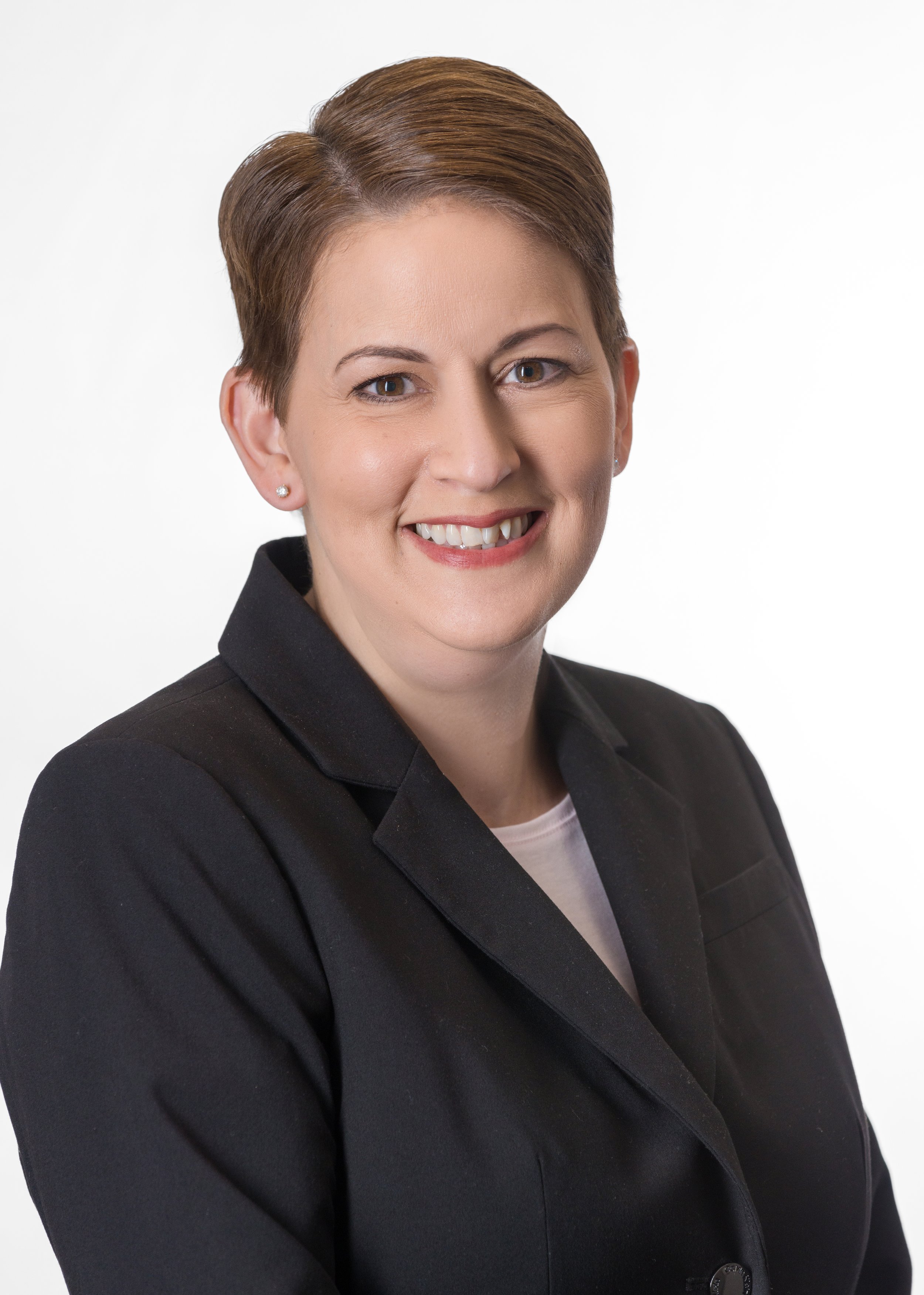 Professional woman with short brown hair wearing a black blazer and white shirt, smiling against a plain white background.