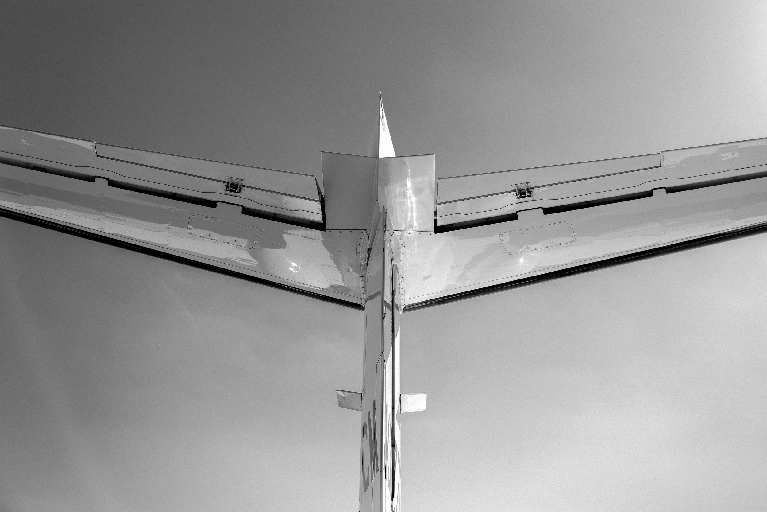 Close-up view of the tail section of an airplane, showing the vertical stabilizer and horizontal stabilizers against a clear sky.