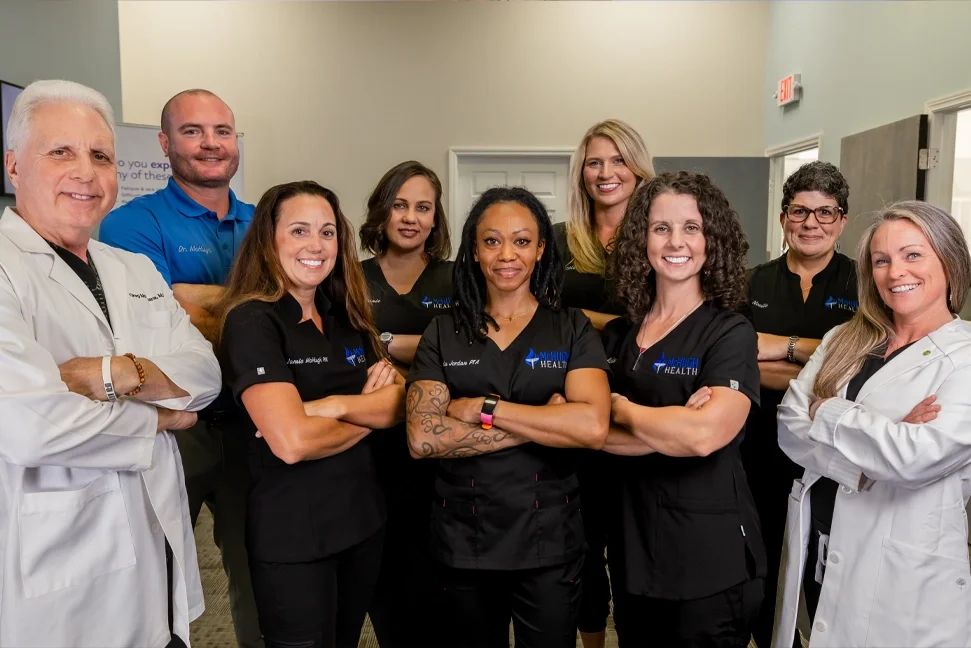 Group of healthcare professionals, including doctors and nurses, posing in a medical office or clinic.