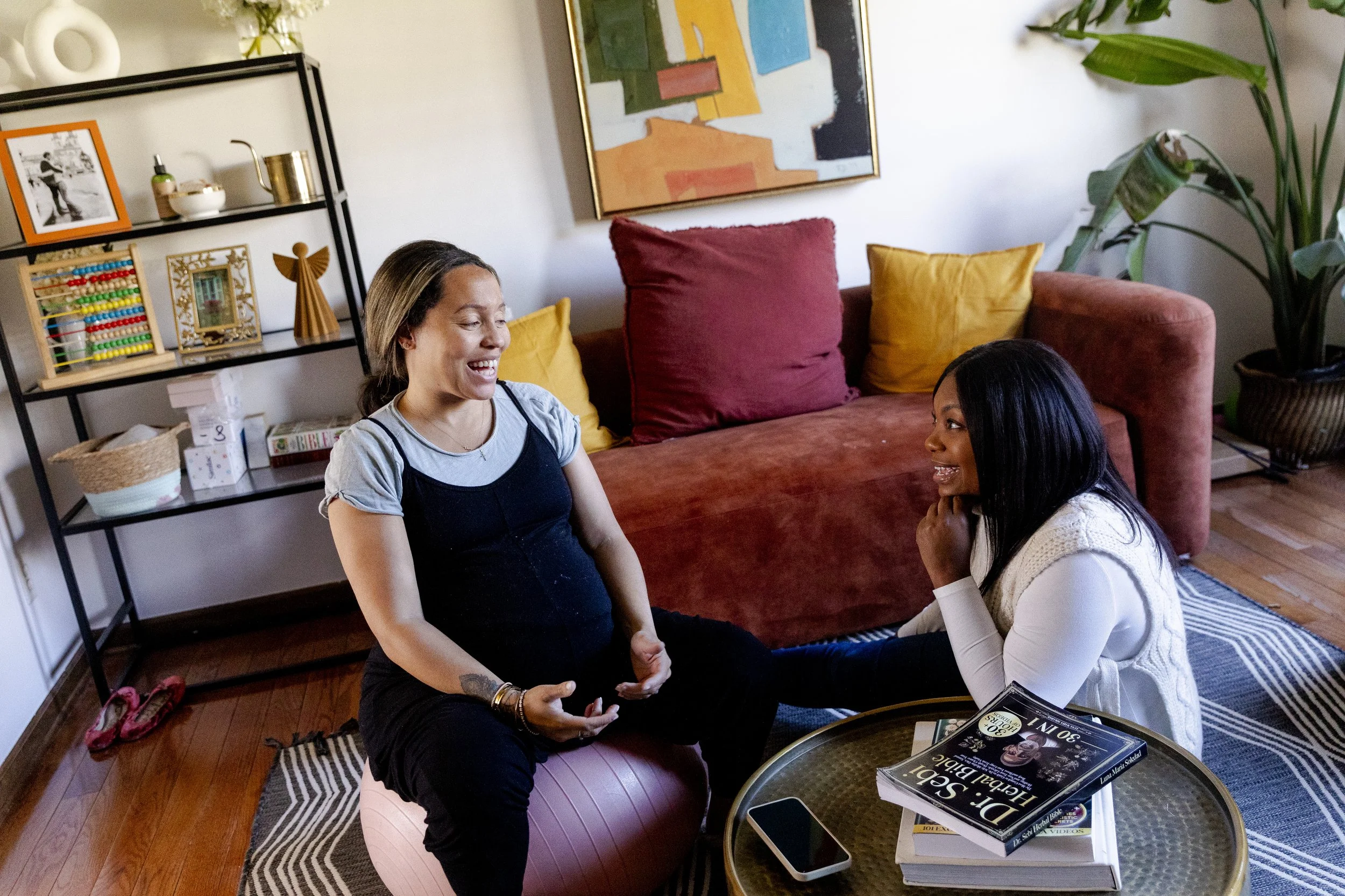 Bree Stallings, Doula, consulting with Mom about delivery while Mom sits on an exercise ball and Bree sits on the floor. 