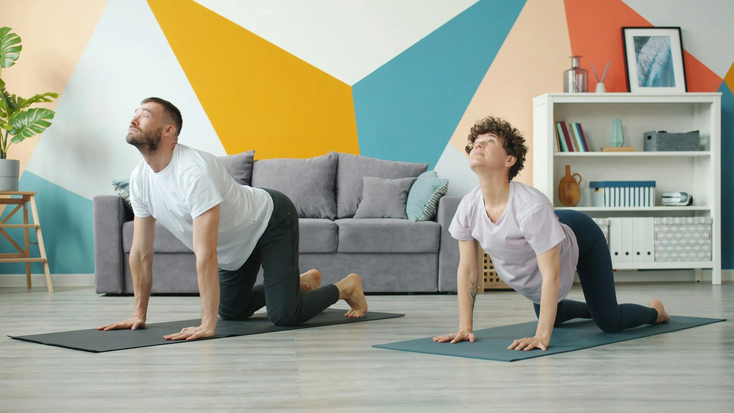 man and woman in living room doing a yoga position