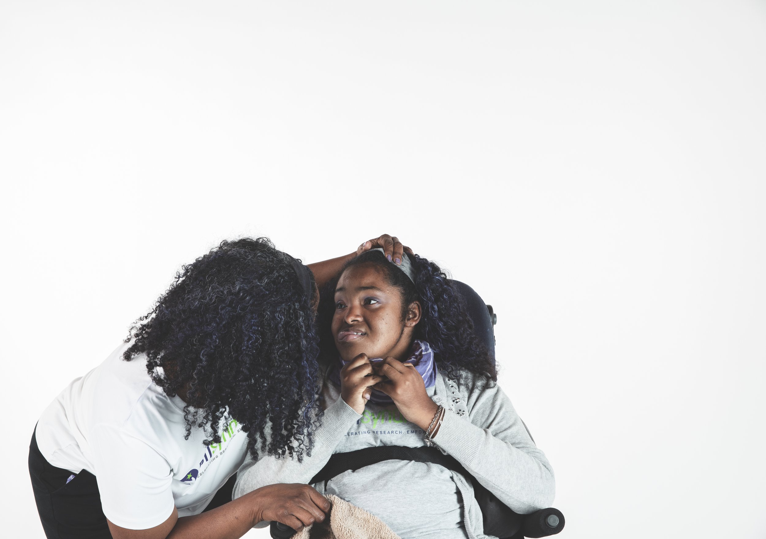 A woman in a wheelchair receives a comforting gesture from a caregiver, who is leaning in to speak or listen.