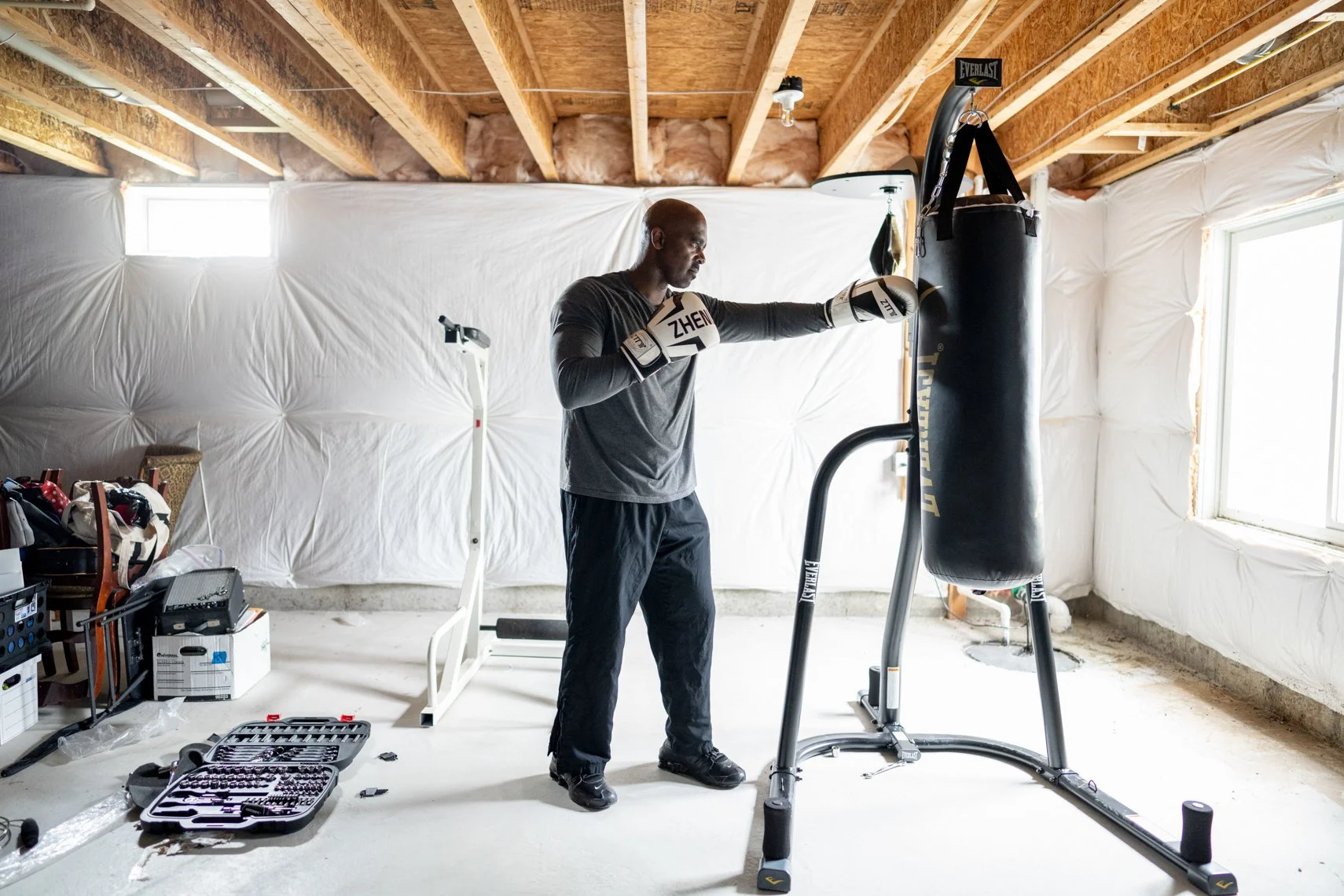 A man practicing boxing in a home gym, hitting a punching bag.