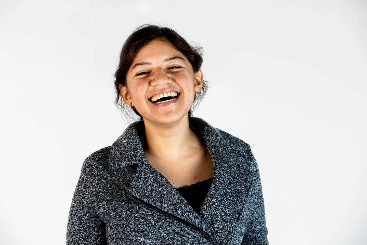 A young woman with dark hair smiling broadly against a plain white background.
