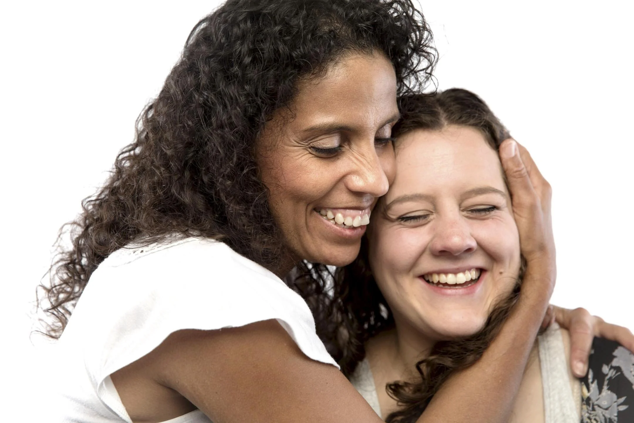 Two women sharing a joyful hug and smile against a white background.