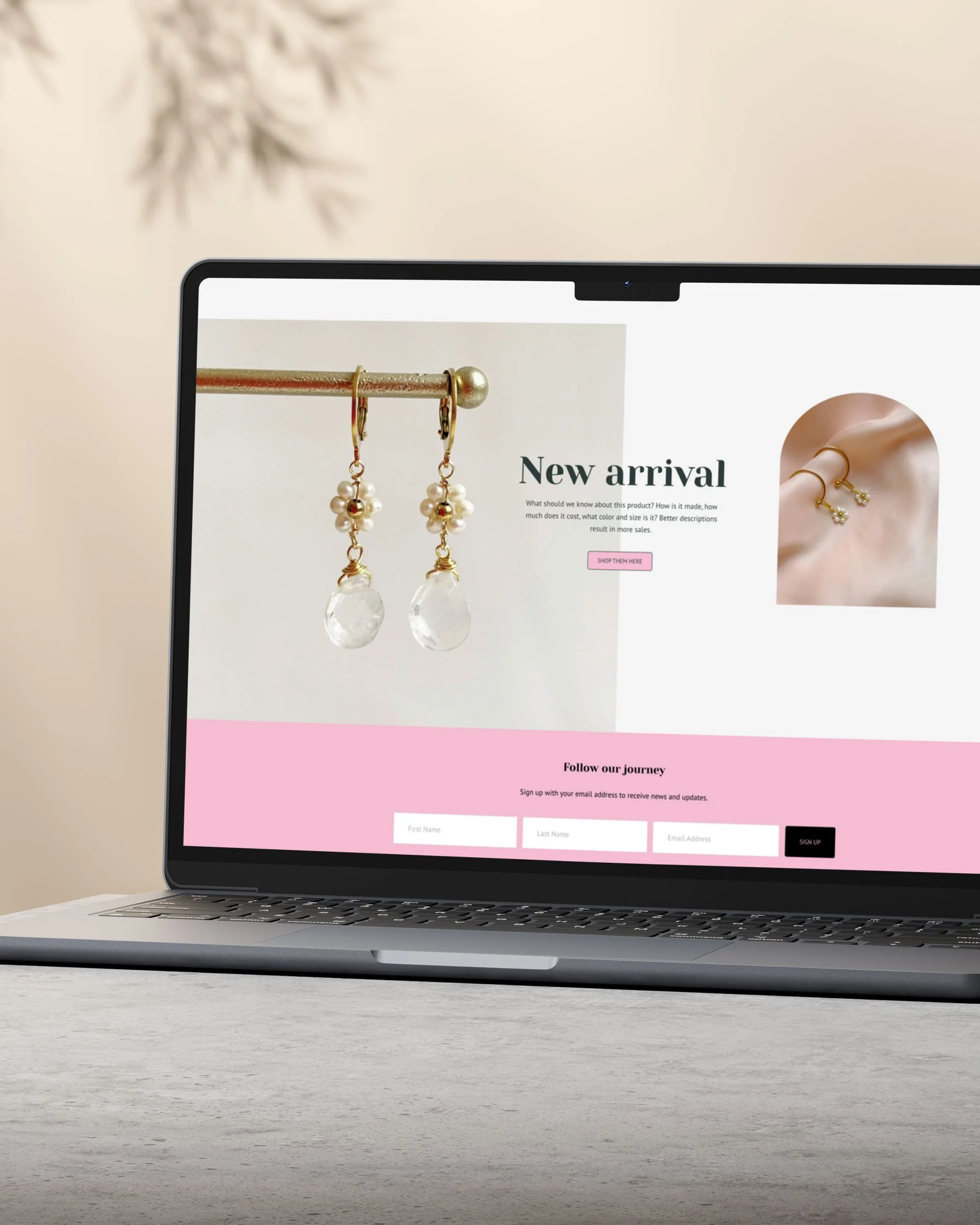 Laptop on a white desk displaying an online jewelry store with an image of pearl and crystal earrings, a pair of gold earrings on an ear, and a pink and white sign-up section.