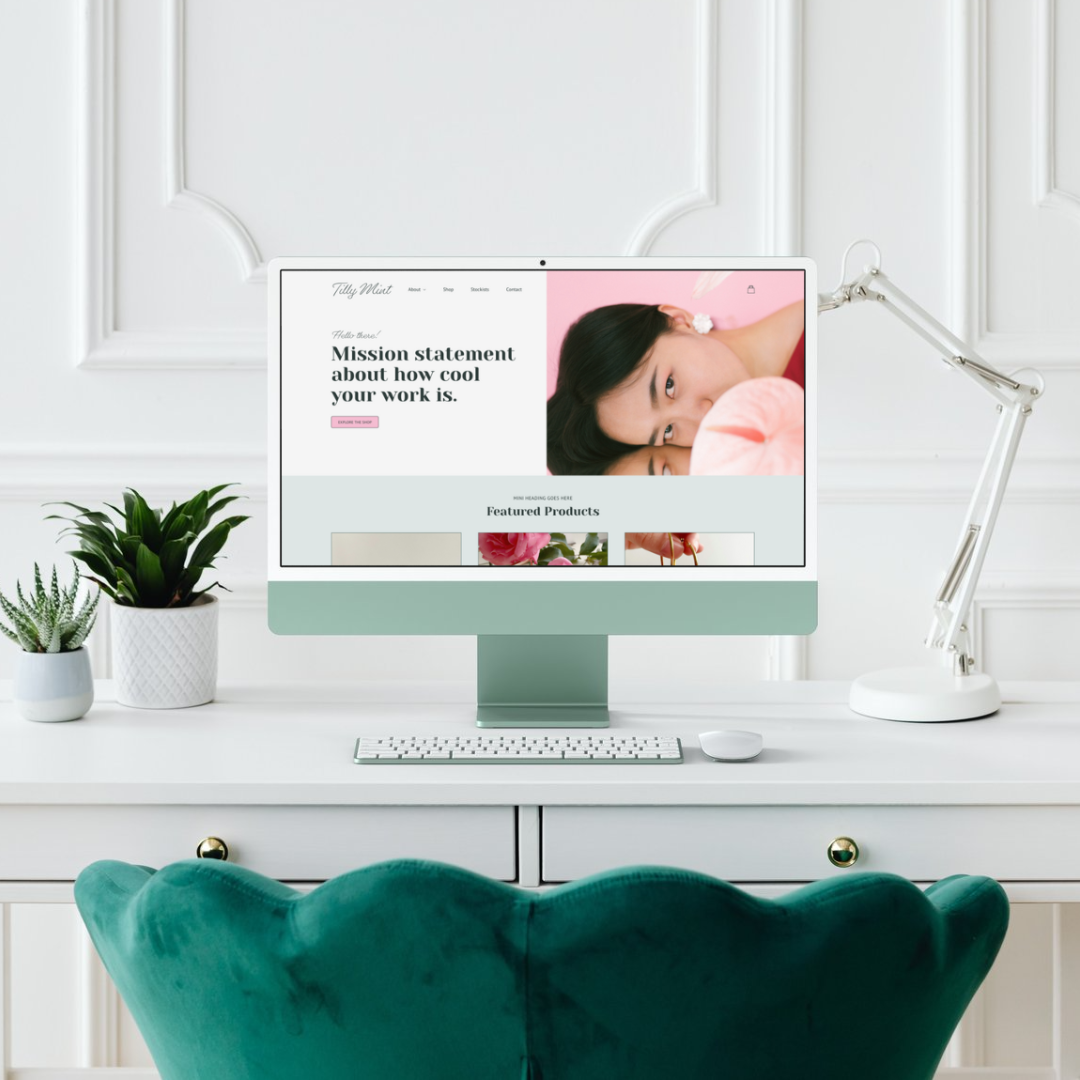 A computer on a white desk in a bright room with a green chair in front. The monitor displays a website with a photo of a woman and books, and has plants on the left.