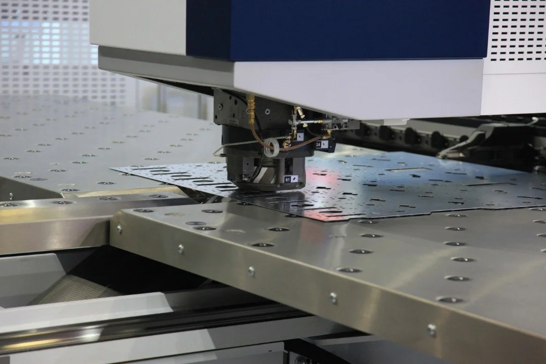 Close-up of a scientific or industrial machine processing a metal sheet with precision tools and mechanisms.