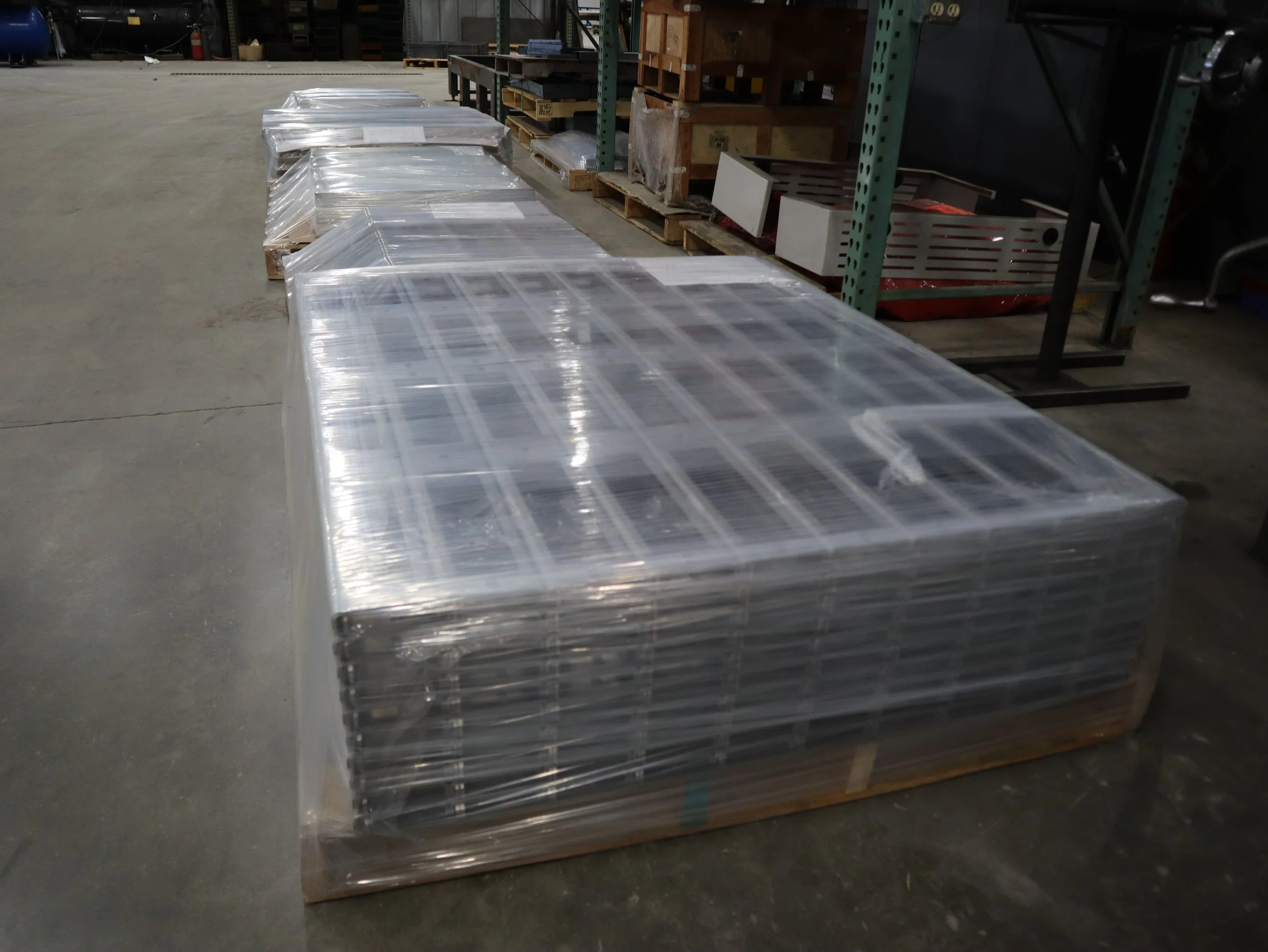 Pallet of metal shelves wrapped in plastic in a warehouse.