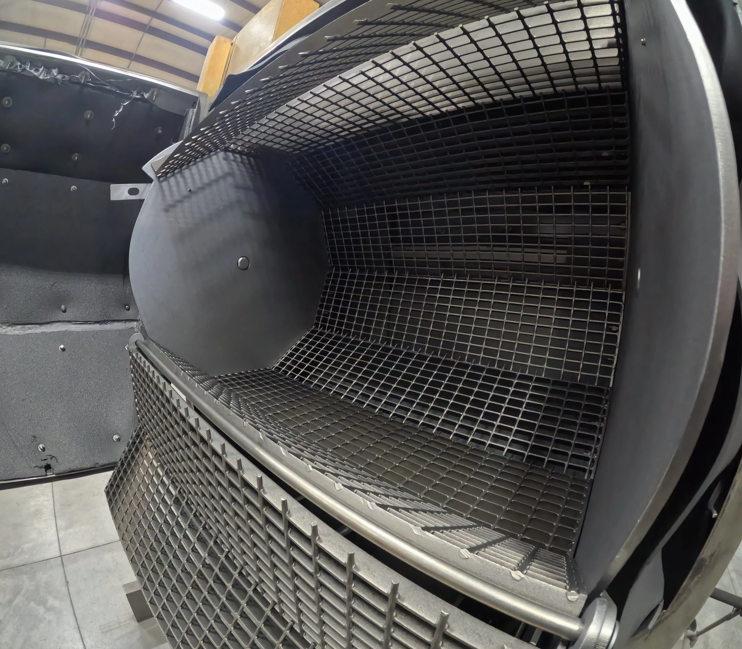 Close-up of a metallic industrial or mechanical part with a grid-like structure and rounded edges, possibly a component of a machine or equipment.