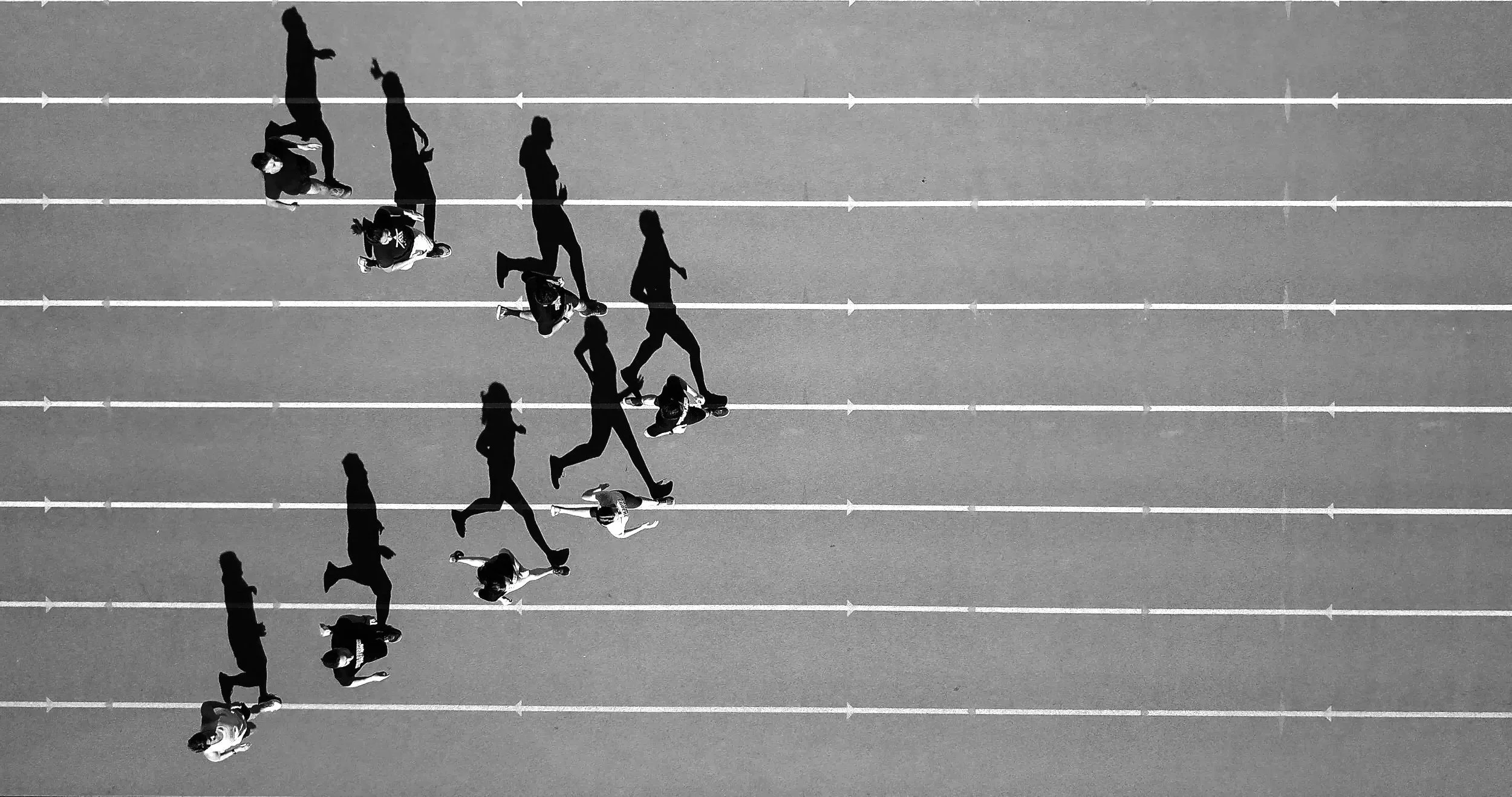 Top-down view of people running and walking on a track.