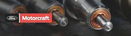 Close-up of multiple automotive fuel injectors on a dark surface with Ford Motorcraft logo
