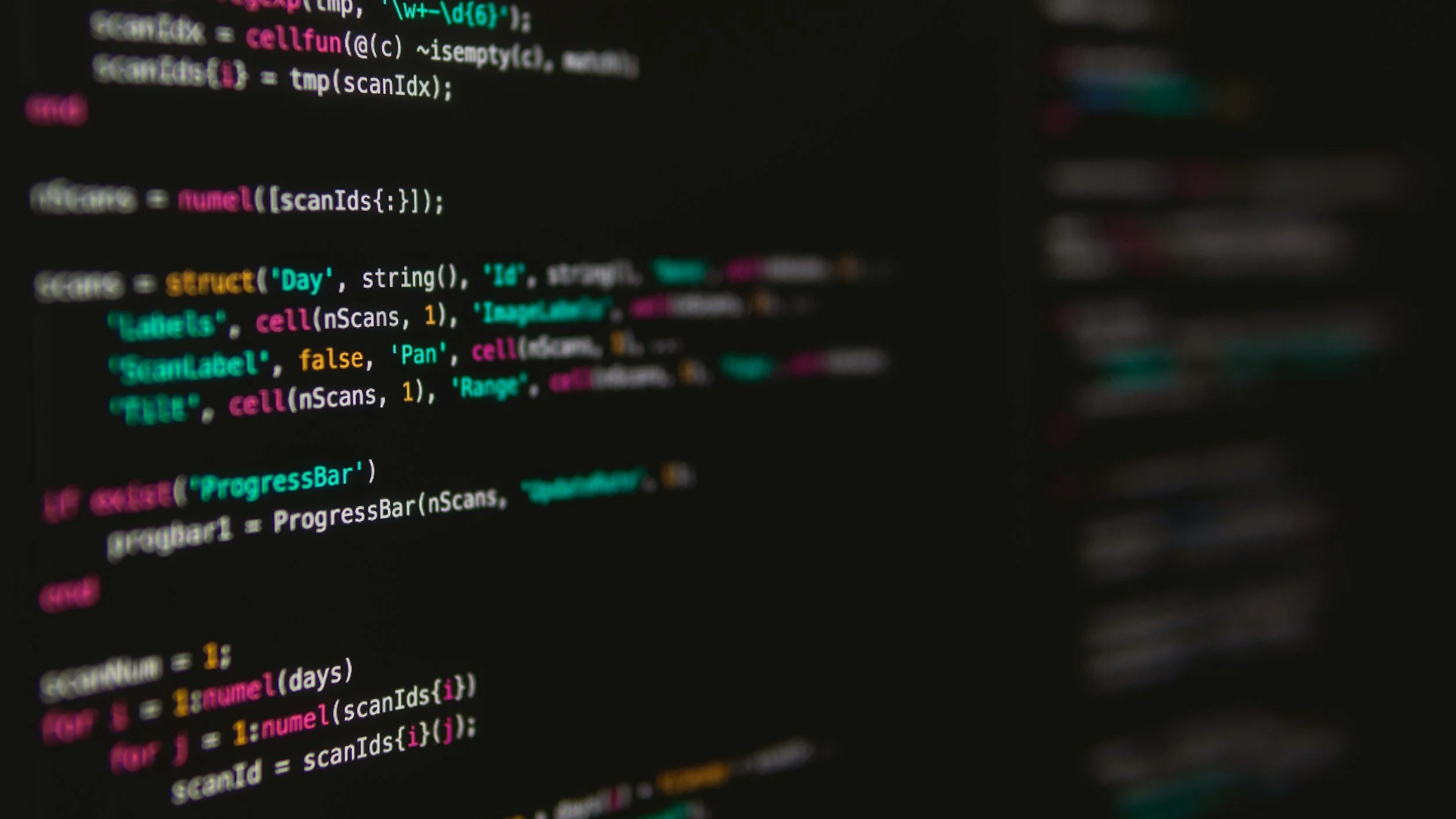 Close-up of a computer screen displaying colorful programming code in a dark environment.