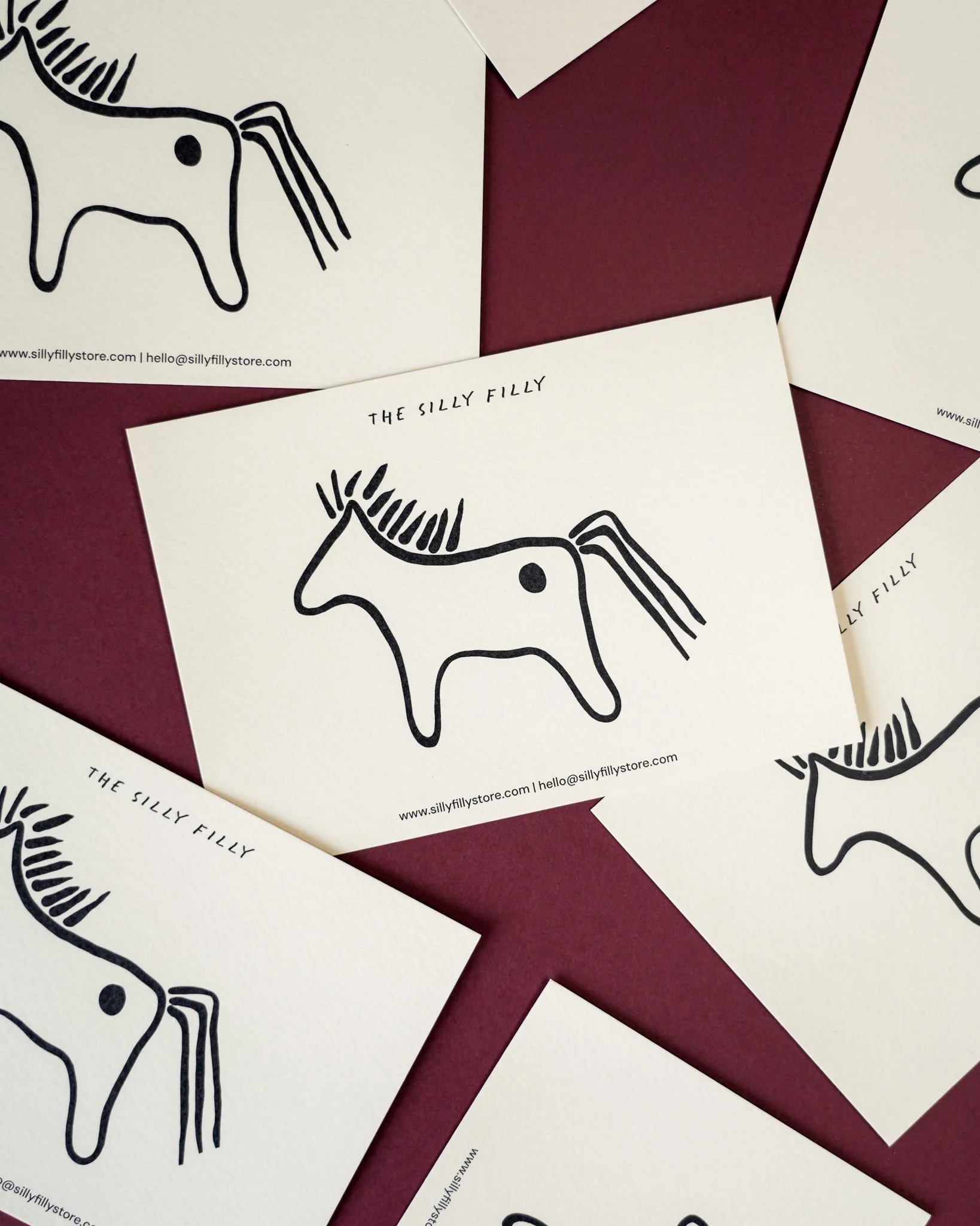 Cards with a black line drawing of a unicorn head, on a red background.